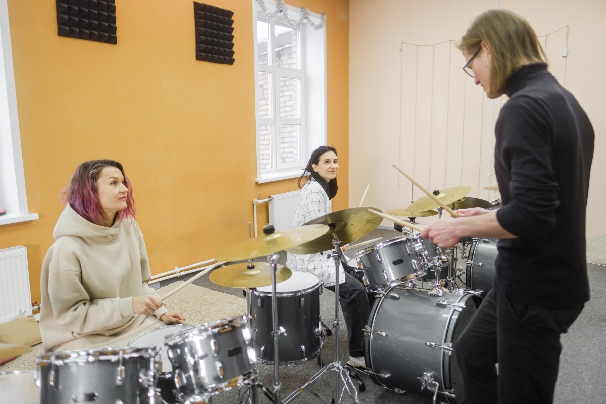 2 Women taking an in-person drum class with a teacher